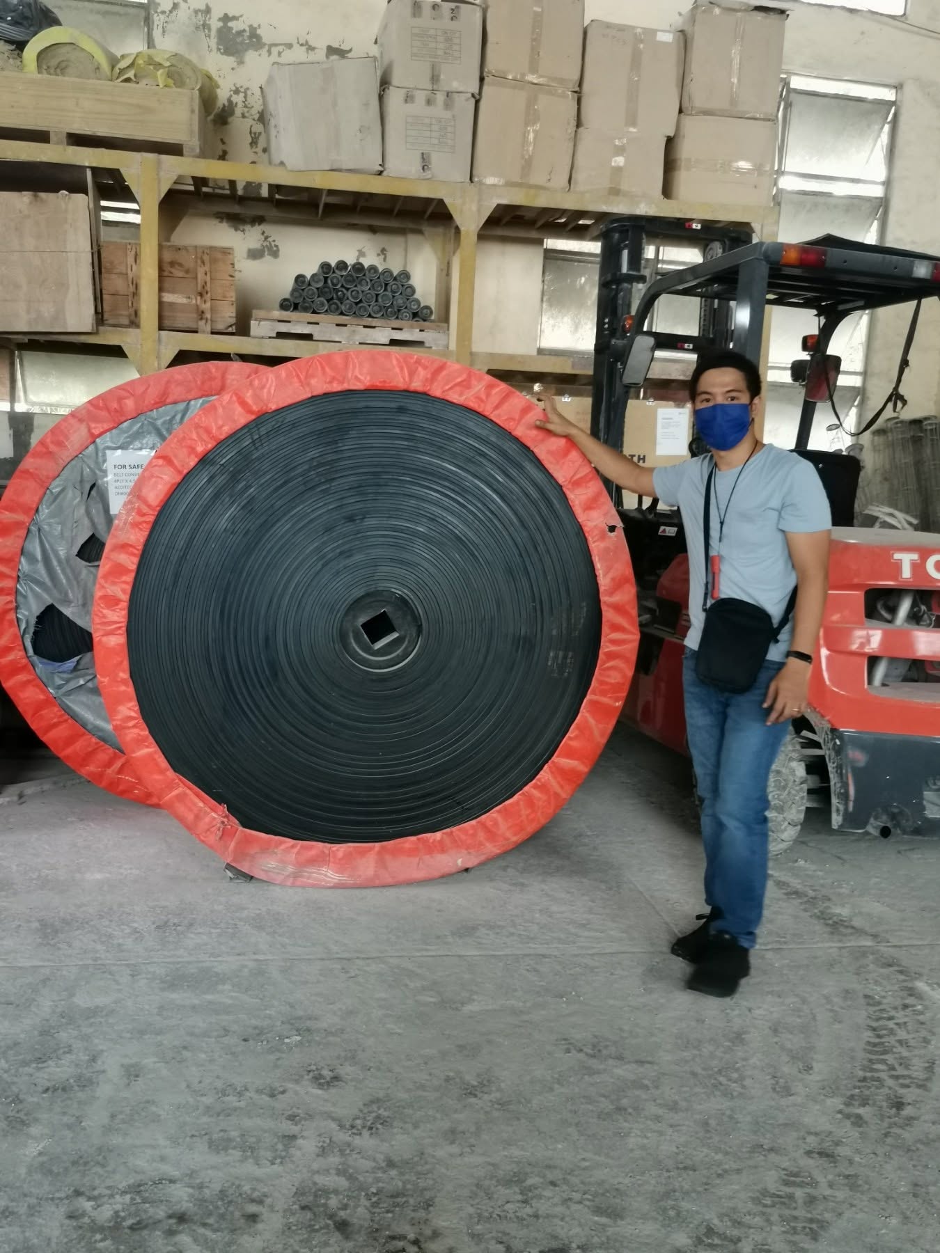 Arditech staff standing beside a large industrial conveyor belt roll in the warehouse