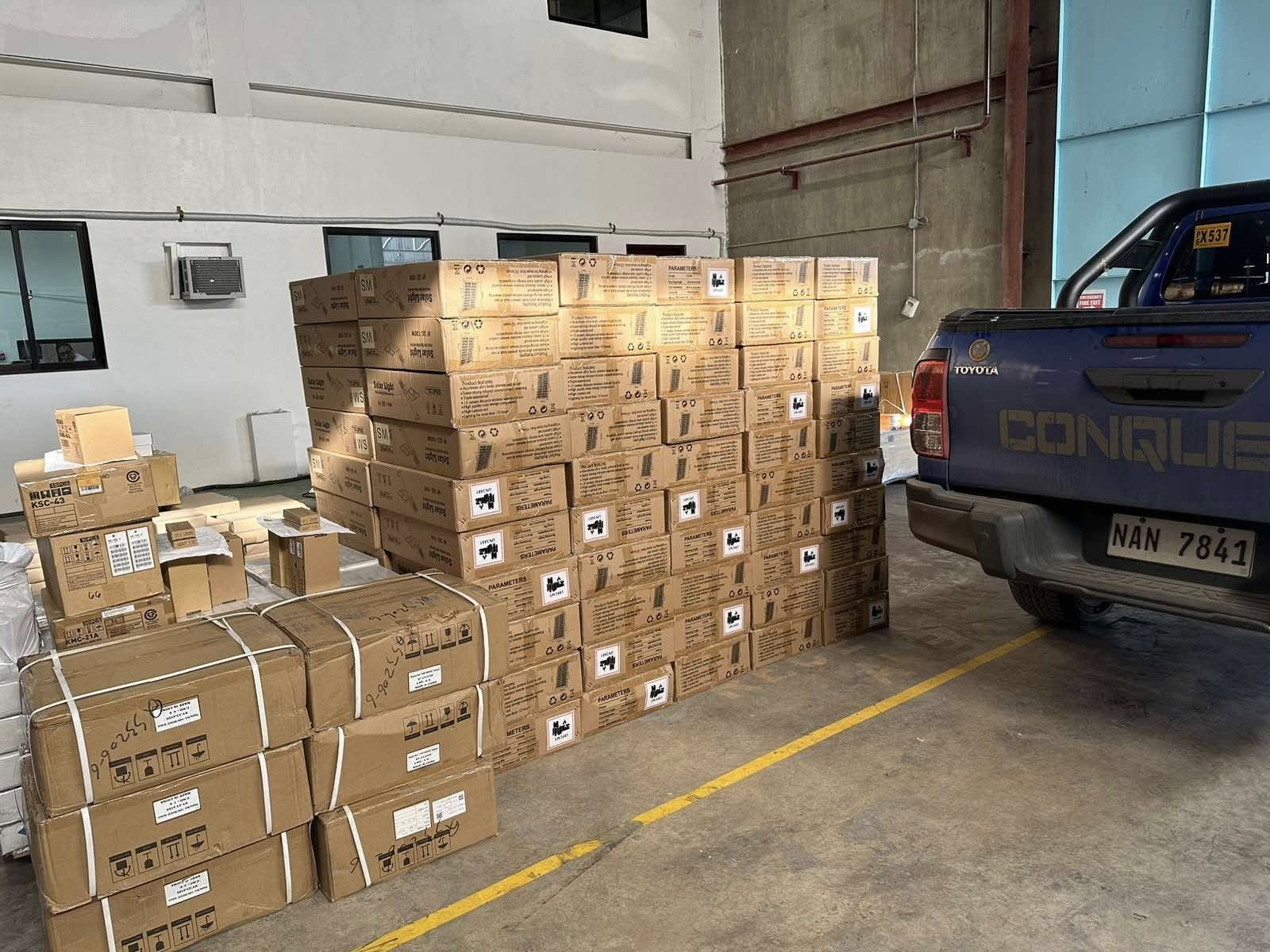 Stacked boxes of solar lights and other stock inside an Arditech warehouse beside a delivery pickup