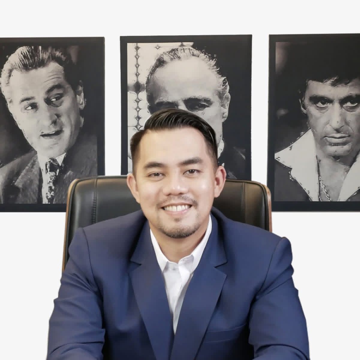 Reymond delos Reyes at his desk with framed portraits of Marlon Brando, Al Pacino, and Robert De Niro on the wall behind him